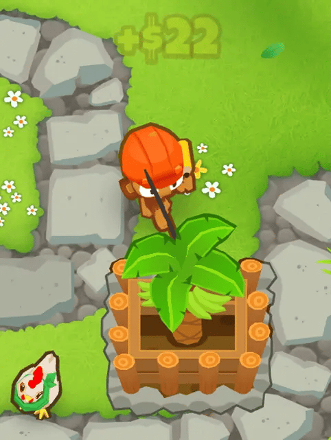 A modded hero in Bloons TD 6, Norman, actively collecting bananas from a Banana Farm. The screen shows Norman, with a chicken nearby, and the addition of +$22 above him indicating collected income.