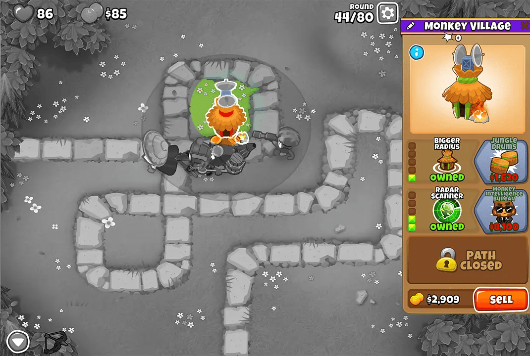 Screenshot of Bloons TD 6 on the Monkey Meadow map during round 44, featuring a Monkey Village tower in the center. The upgrade menu for the Monkey Village is displayed on the right side of the screen.