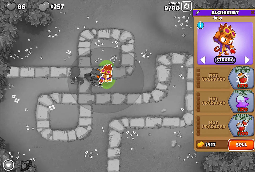 Screenshot of Bloons TD 6 on the Monkey Meadow map during round 9, with an Alchemist tower highlighted and upgrade options displayed. The game interface shows $257 and 86 lives remaining.